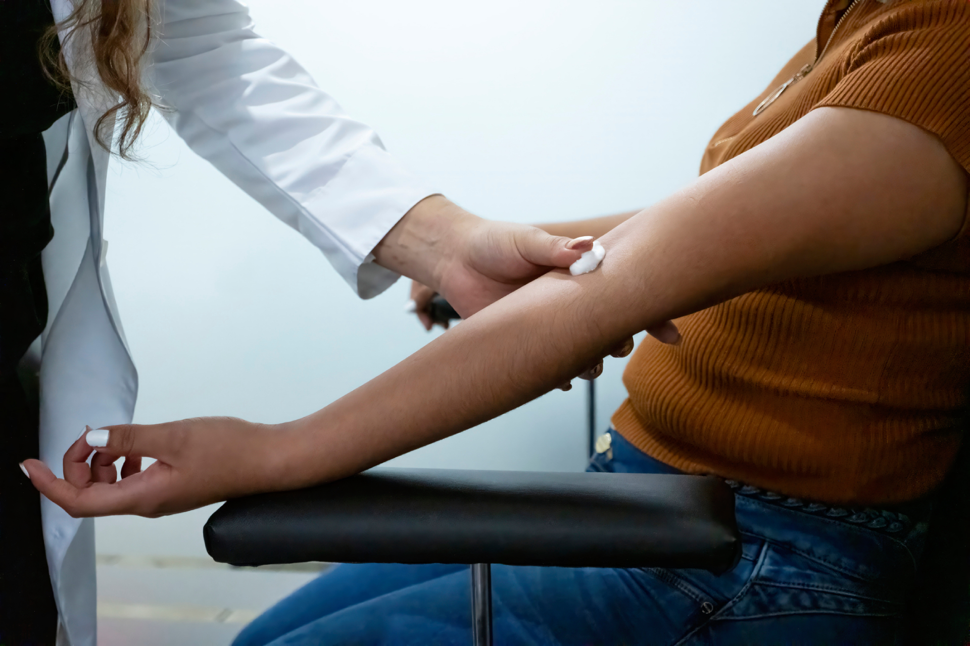 A nurse putting a cotton pad on a woman’s arm after a blood draw