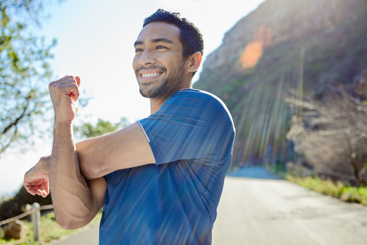 Client smiles and stretches after running on scenic roadway