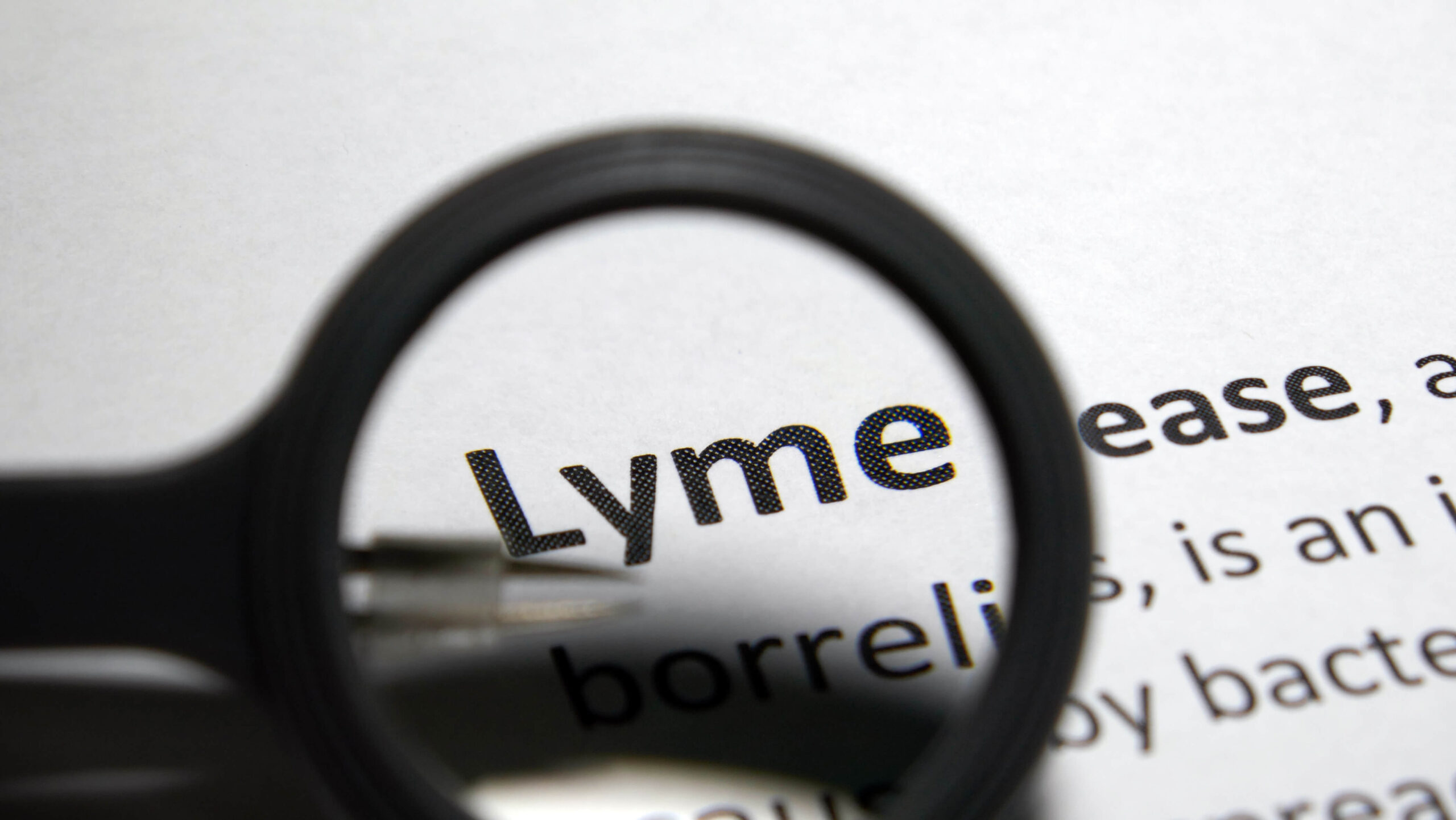 Closeup of a magnifying glass above a paper with the definition of Lyme disease