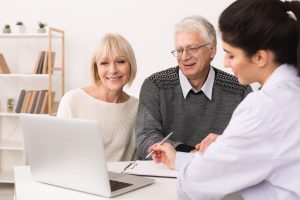 elderly couple consulting with a female doctor at a desk