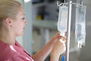 blonde female nurse preparing an IV drip