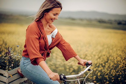 Young woman riding a bike through a field of flowers