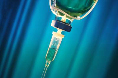 An IV drip with a blue curtain background