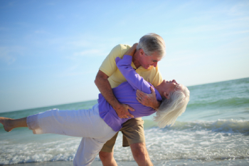 Senior couple dancing on a beach with ocean in background