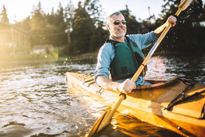 Smiling man kayaking at dusk