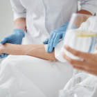 Close up of woman holding glass of lemon water while getting IV infusion