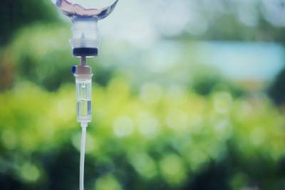 Saline intravenous drip bag in front of blurred outdoor background