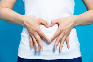 Close-up of a woman making a heart shape with her hands in front of her stomach
